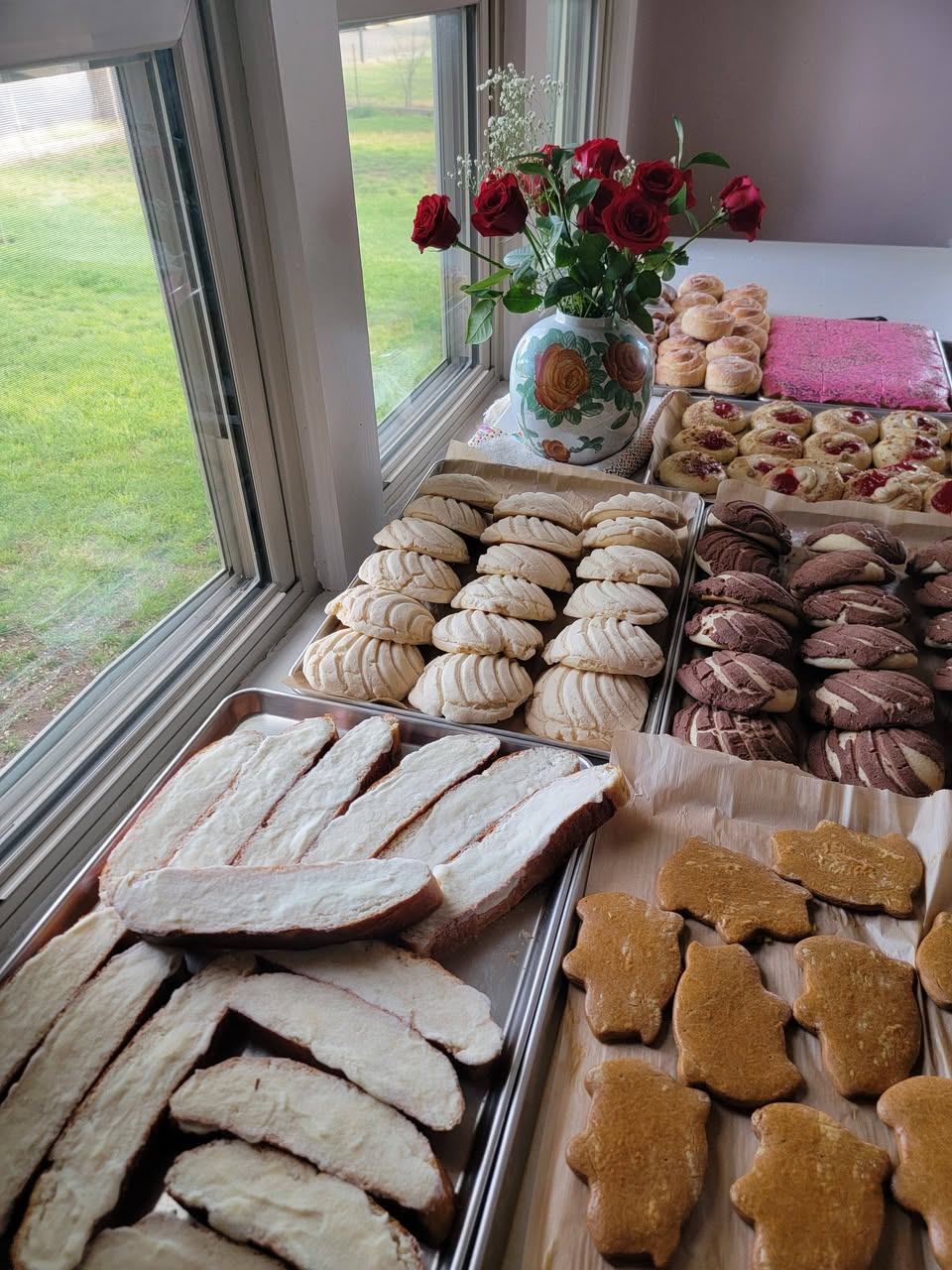 Charolas de pan dulce junto a la ventana con rosas